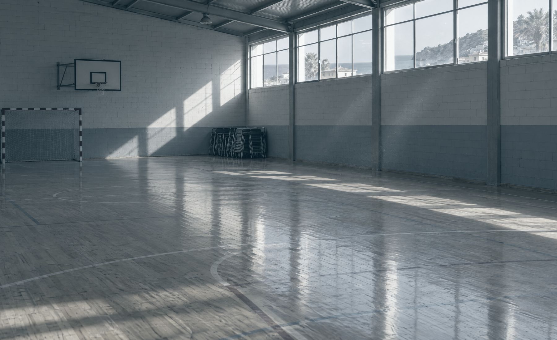 Pabellón deportivo vacío con la luz de la tarde entrando por los ventanales